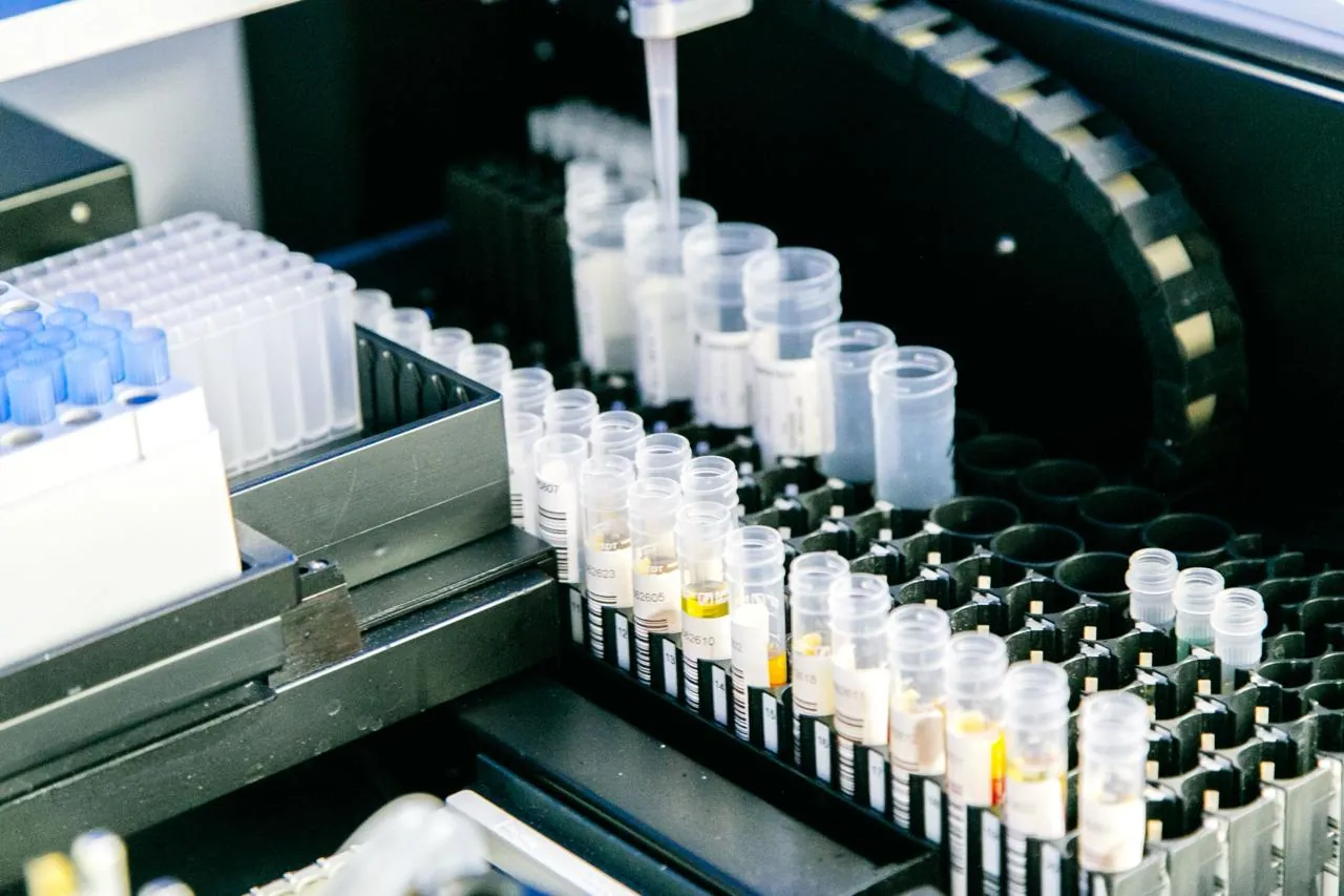 Automated liquid-handling robot pipetting into racks of barcoded assay sample tubes